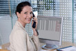 © carlosseller - Confident businesswoman speaking on phone at her computer