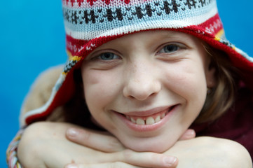 Wall Mural - Young girl wearing woolen cap, scarf and gloves on blue