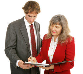 Female boss signing off on a report  by a young businessman. 