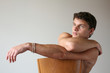 © Vladimir Wrangel - Sexy muscular man sitting on the wooden chair. Copy space