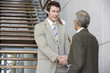 © carlosseller - Two businessmen shaking hands on a staircase