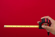 © Karen Roach - Tape measure in hand on red background with copy space