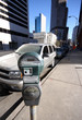 Parking meter in downtown area in front of silver vehicle