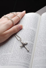 holy bible open with a cross on a hand