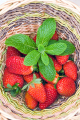 Poster - a wooden basket with red strawberry and green mint leaves