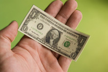 A Hand Holding A Miniature United States One Dollar Bill 