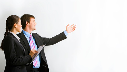 Portrait of businessman pointing at wall with her assistant 