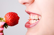 Abgebissene Erdbeere zwischen Zähnen von Frau