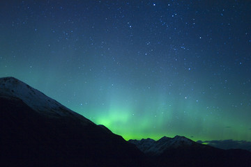 Wall Mural - Northern lights making the sky green over the tops of mountains