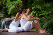 © EastWest Imaging - A young couple in white sitting outside with a tropical backdrop