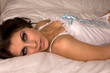 closeup of woman lying on bed in white corset beautiful eyes