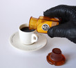 Hand in black leather glove strewed poison in cup of coffee