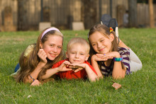 Three Children On A Lawn In Park