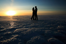 Couple Holding Hands Against Sunset On Frozen Sea