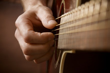 Hand playing acoustic guitar