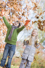 Two Children Throwing Leaves In The Air