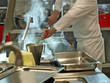 Professioneller Koch, der einen dampfenden heißen Topf mit Essen in der Gastronomie-Küche umrührt