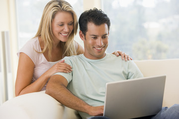 Couple in living room using laptop smiling