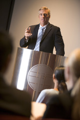 Wall Mural - Businessman giving presentation at podium