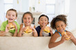 Four young children eating cheeseburgers smiling