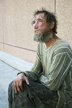 Sad Homeless Man Sitting On At The Wall On City Street