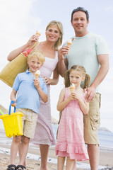 Wall Mural - Family standing at beach with ice cream smiling