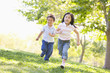 © Monkey Business - Brother and sister running outdoors smiling