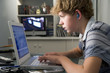 © Monkey Business - Young boy in bedroom using laptop and listening to MP3 player