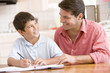 © Monkey Business - Man helping young boy in kitchen doing homework and smiling