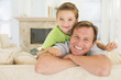 © Monkey Business - Man and young boy sitting in living room smiling