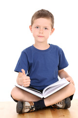 Wall Mural - 6-7 years old boy sitting with book isolated on white