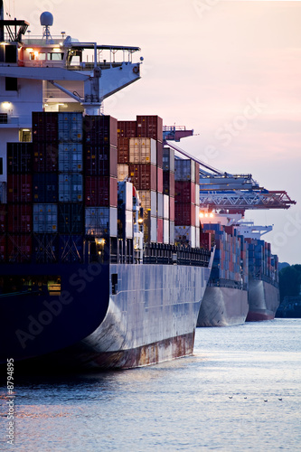 Fotografie, Obraz container cargo ships docked in port - three freighters sunset