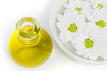 body oil and beautiful white daisies floating in a bowl of water