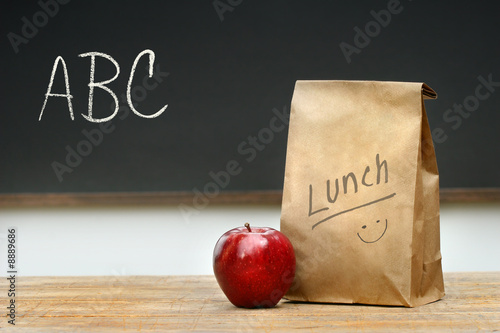 Fotografía Paper lunch bag on desk with apple