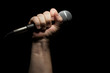 © Andy Dean - Microphone clinched firmly in male fist on a black background.