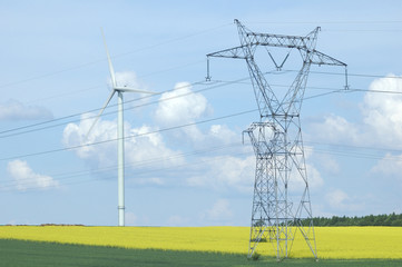 A electric pylon near windturbine over rape field France