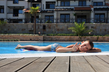 Smiling Boy Lies On The Edge Of Swimming Pool.