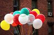 bunch of helium balloons in front of brick