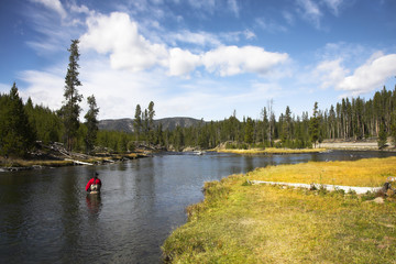 The fisherman in a red diving suit in the cold autumn river