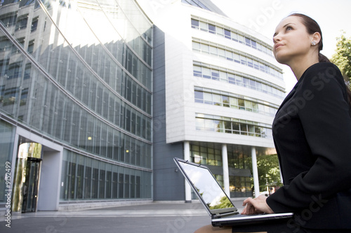 Foto Businesswoman using laptop outside office