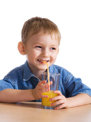 Wall Mural - Laughing little boy drinking orange juice..