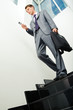 © pressmaster - Below view of businessman in suit with cellular phone