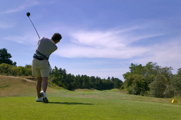 Shot of a male golfer teeing off with the ball in mid air