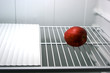 one red delicious apple alone in an empty refrigerator