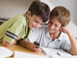 © Monkey Business - Two Young Boys Distracted From Homework, Playing With Cellphone