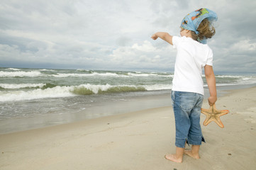 Wall Mural - Little girl with starfish on the beach