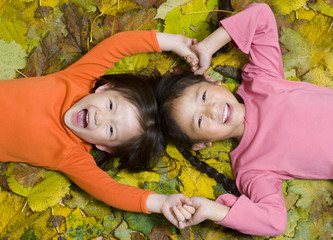 Two sisters playing in the autumn leaves