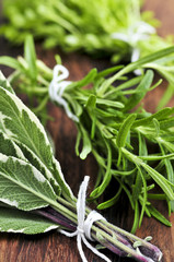 Wall Mural - Bunches of assorted fresh herbs close up on wooden cutting board