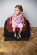 Happy little girl sitting on top of a pile of suitcases