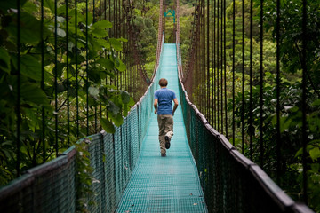 young man running over a jungle bridge